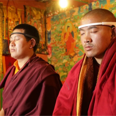 Two monks meditating while wearing Muse headband